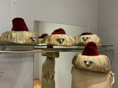 trois chapeaux posés sur une étagère en verre