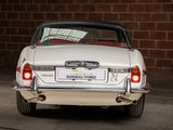 a white car parked in front of a brick wall