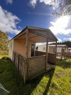 une petite cabane en bois avec un porche couvert, au milieu de l'herbe