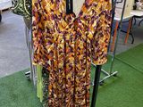 dress hanging on a rack in a clothing store next to a rack of clothes