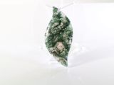 un objet vert en forme de feuille posé sur un socle transparent