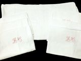 quatre serviettes blanches ornées de broderies roses sur fond noir