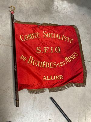 a red and gold banner on the floor next to a pair of scissors