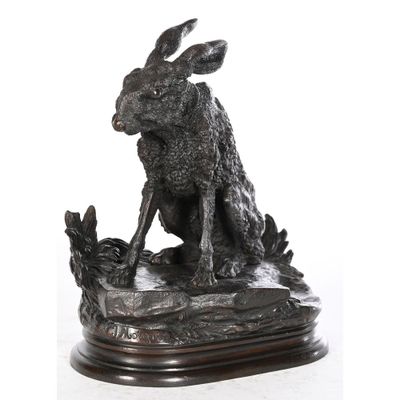 une statue représentant un lapin assis sur un socle en bois