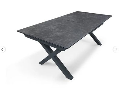 une table noire aux pieds en forme de croix sur fond blanc