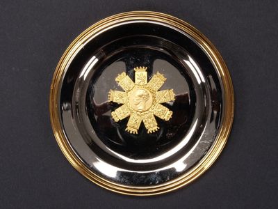 une assiette noire ornée d'une fleur dorée