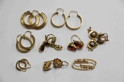 plusieurs paires de boucles d'oreilles et de bagues en or posées sur un fond blanc