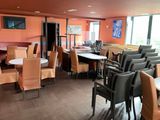 tables and chairs in a restaurant with orange walls and wood flooring