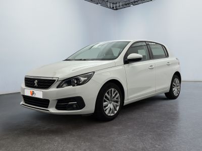 La voiture blanche est garée dans une grande pièce au sol noir.