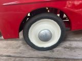 a red toy car with a white wheel on a wooden table