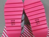 pair of pink flip flops on a pink and white striped surface