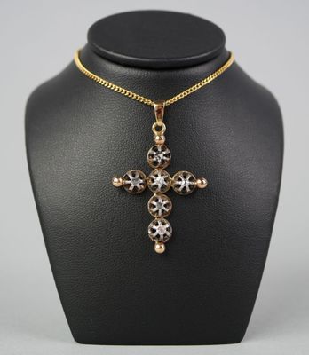 un collier noir et doré orné d'une croix, posé sur un mannequin