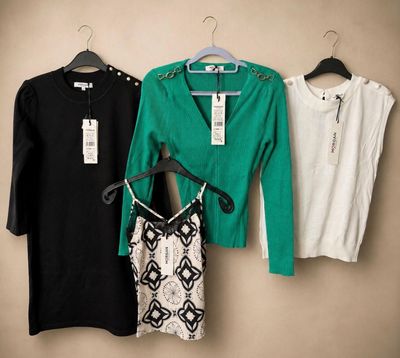 three women ' s sweaters hanging on a hanger in front of a wall