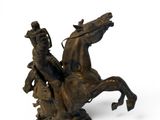 a bronze statue of a man on a horse holding a gun