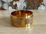 un gros plan d'un bracelet en or posé sur une table en bois