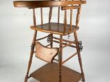 an old wooden high chair sitting on top of a wooden shelf