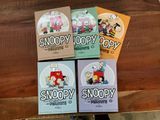 quatre livres de Snoopy et Snoopy posés sur une table en bois