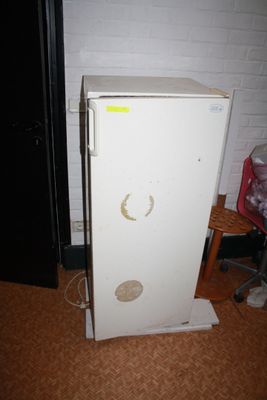 un réfrigérateur blanc avec un autocollant jaune sur la porte