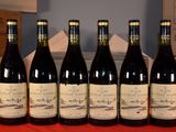 six bottles of red wine are lined up on a table