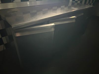 une table sur laquelle est posé un ordinateur portable, dans une pièce sombre
