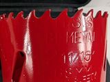 a close up of a red hole saw on a table