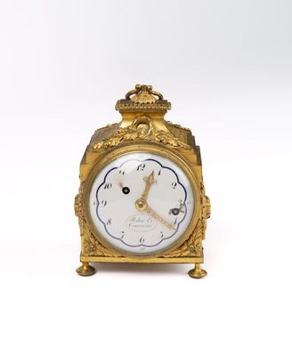 a gold clock that is sitting on a white surface