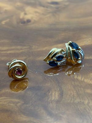 deux paires de boucles d'oreilles posées sur une table en bois, parsemées de gouttelettes d'eau