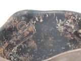a rusted metal bowl sitting on a white surface