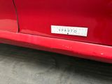 the rear end of a red car with a sticker on it ' s bumper
