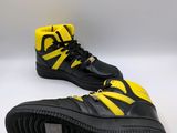 a pair of black and yellow sneakers on a white surface