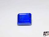 un gros plan d'une pierre bleue de forme carrée posée sur une surface blanche