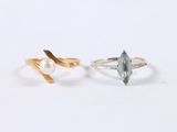 two rings with a pearl and a leaf on a white background