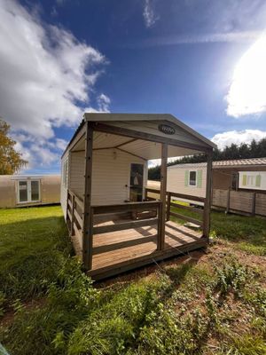 deux mobil-homes situés dans un espace verdoyant, avec des arbres en arrière-plan