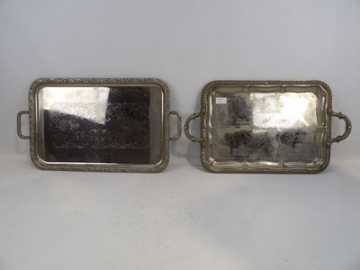 deux plateaux en argent munis d'anses, posés sur une surface blanche