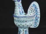 un petit poulet bleu et blanc dans un bol, sur fond noir
