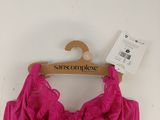 La bralette rose est suspendue à un cintre accroché au mur.