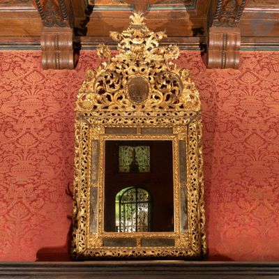 un miroir posé sur une cheminée devant un mur rouge
