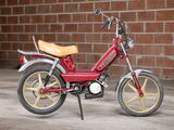 a small red motorcycle parked in front of a brick wall