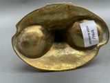 brass sculpture of two eggs in a shell with a label on it