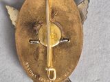 a gold pin with a cross on it on a white surface