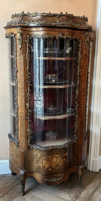 a glass display cabinet in the corner of a room