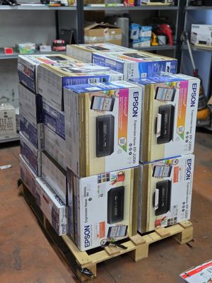 Plusieurs cartons contenant des appareils électroniques sont empilés sur des palettes dans un entrepôt.