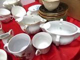 many cups and saucers sitting on a red table cloth
