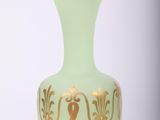 a green vase with gold decoration on it on a white surface