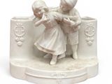 une figurine blanche représentant deux enfants en train de jouer ensemble