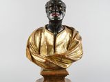 bronze bust of a man in a gold shirt on a wooden base