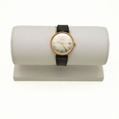 un gros plan d'une montre-bracelet posée sur un présentoir blanc