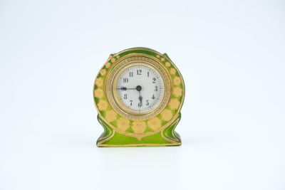 a small green and gold clock sitting on a white surface