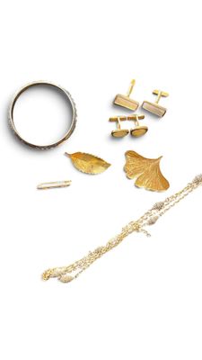 a gold bracelet, ring, and other jewelry on a white surface