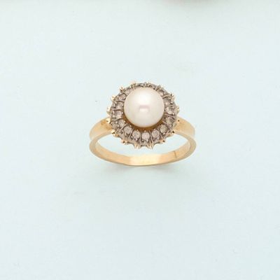 two gold rings with pearls and diamonds on a white surface